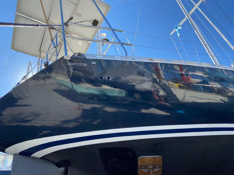Slide: The Image of 1984 Beneteau First 42 sailboat with dark hull, docked under clear blue sky. - 6