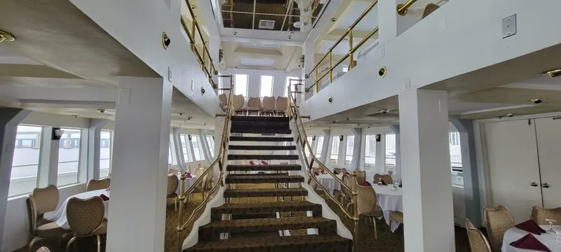 Slide: The Image of Interior of 1979 Blount 130 Dinner Cruise ship with elegant dining setup and central staircase. - 11
