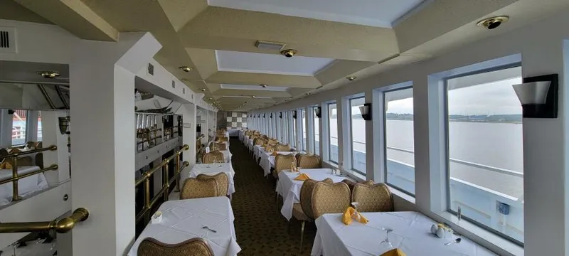 Slide: The Image of Elegant dining area on Blount 130 Dinner Cruise, featuring panoramic windows and neatly set tables. - 14