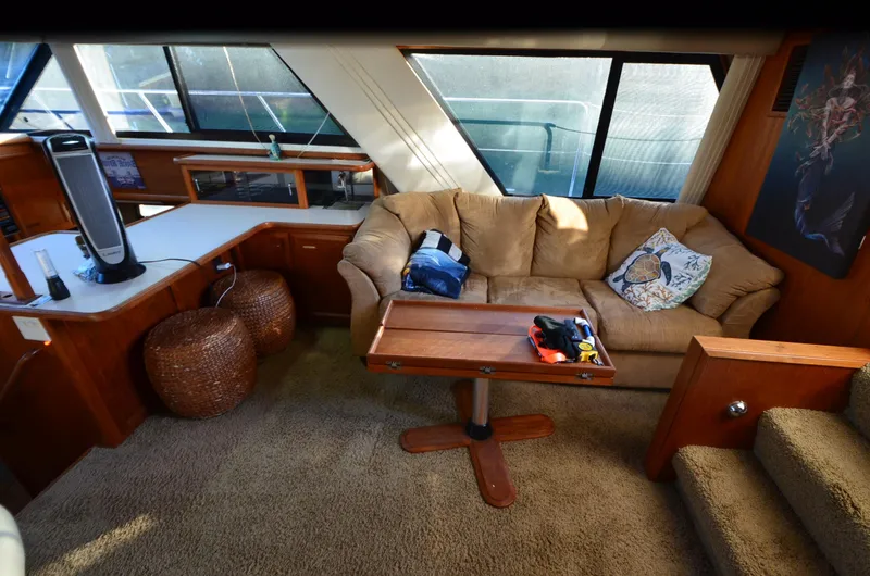 Slide: The Image of 1988 Carver 4207 Aft Cabin MY interior with beige sofa, wooden table, and large windows. - 15