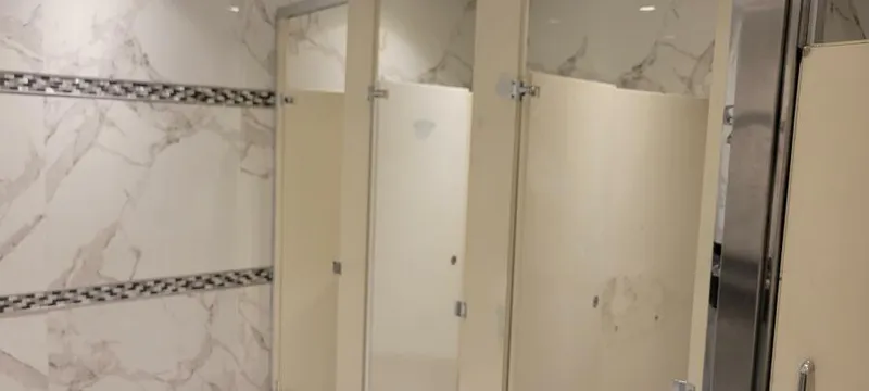 Slide: The Image of Public restroom stalls with marble-patterned walls and beige doors. - 17