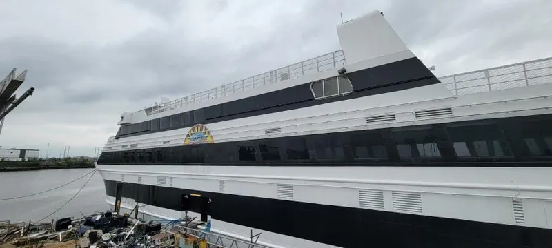 Slide: The Image of Custom Victory 11 ship, 1981 model, docked by the river under cloudy skies. - 3