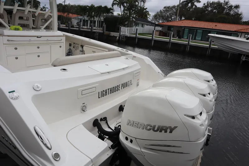 Slide: The Image of 2022 Boston Whaler 380 Outrage with triple Mercury engines docked by waterfront homes. - 10