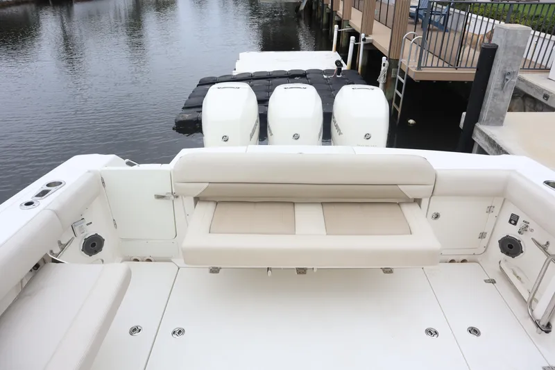 Slide: The Image of 2022 Boston Whaler 380 Outrage boat with triple engines docked by the water. - 12