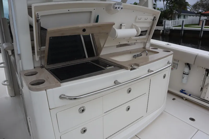 Slide: The Image of 2022 Boston Whaler 380 Outrage boat kitchen area with grill and storage drawers. - 14