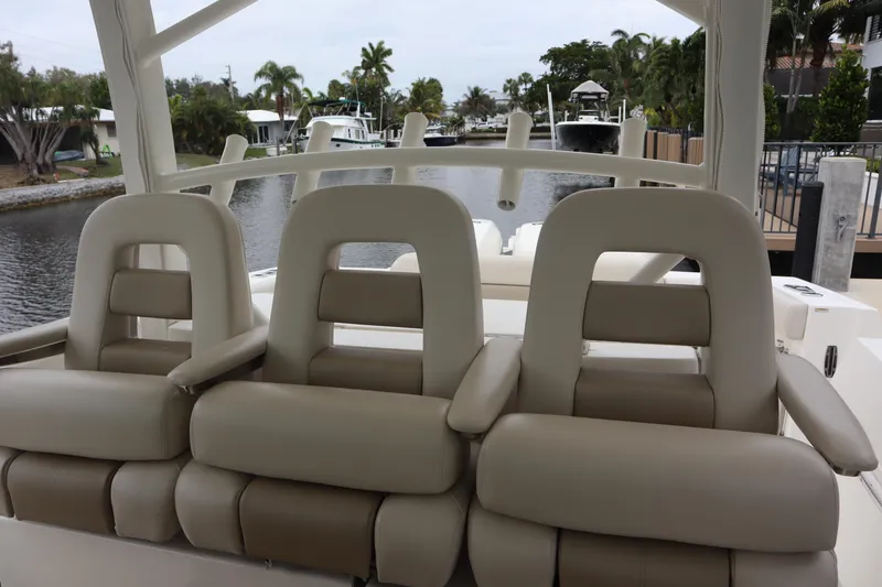 Slide: The Image of 2022 Boston Whaler 380 Outrage boat seats, docked by a canal with palm trees. - 18