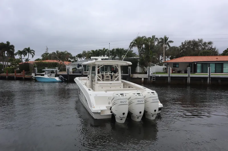 Slide: The Image of 2022 Boston Whaler 380 Outrage boat with triple engines on a calm waterway. - 2