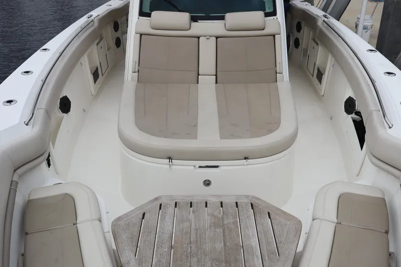 Slide: The Image of 2022 Boston Whaler 380 Outrage boat interior with cushioned seating and wooden deck. - 23