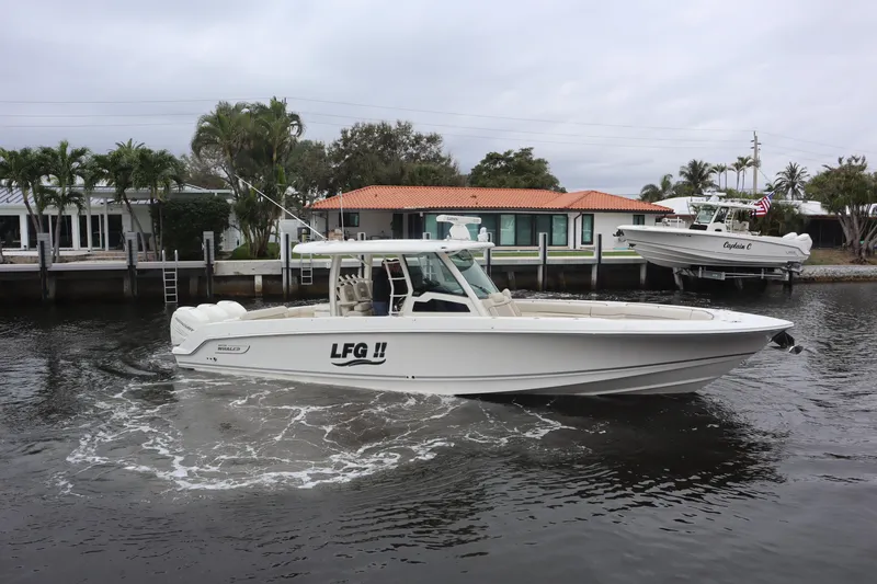 Slide: The Image of 2022 Boston Whaler 380 Outrage boat cruising on a calm waterway near waterfront homes. - 5