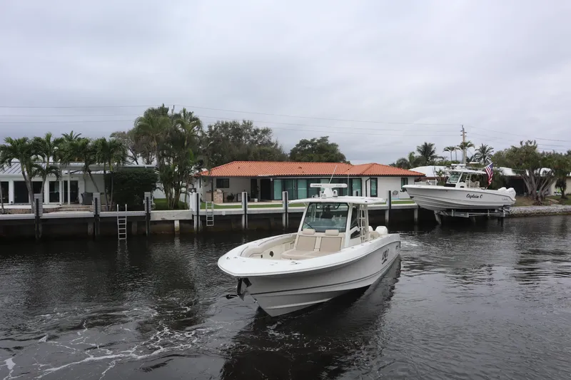 Slide: The Image of 2022 Boston Whaler 380 Outrage boat on a calm waterway near waterfront homes. - 8
