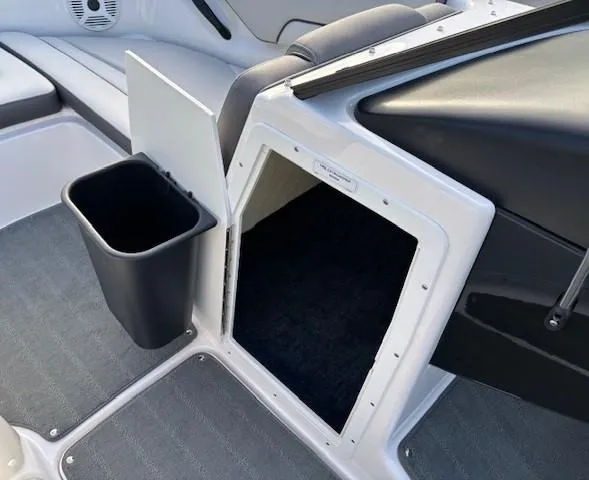 Slide: The Image of 2020 Yamaha Boats SX190 interior storage compartment with trash bin and seating area. - 19