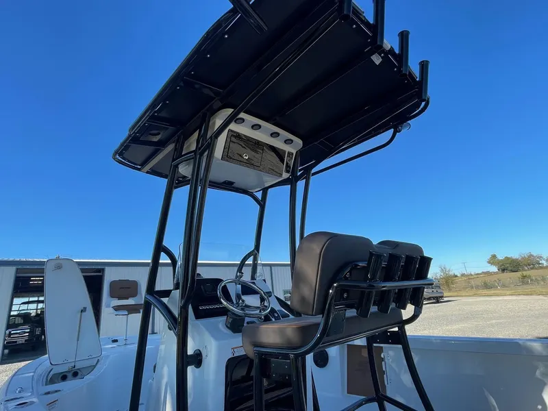 Slide: The Image of 2025 Sea Pro 210 DLX boat console with T-top and seating, under clear blue sky. - 10