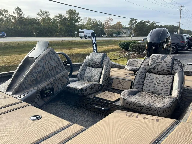 Slide: The Image of 2025 Xpress H18 Bass boat interior with camo seats and steering console. - 10