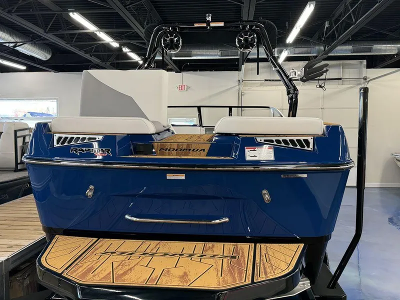 Slide: The Image of 2025 Moomba Mojo boat in showroom, blue exterior, rear view. - 13