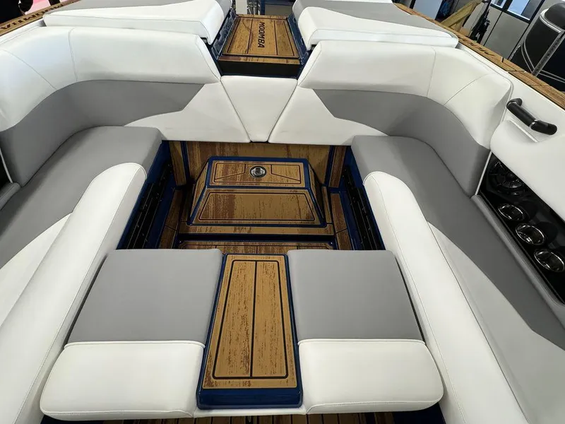 Slide: The Image of 2025 Moomba Mojo boat interior with white and gray seating, wood accents, and cup holders. - 21