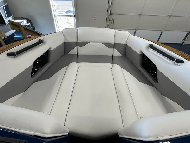 Slide: The Image of 2025 Moomba Mojo boat interior with white and gray seating in a showroom. - 24
