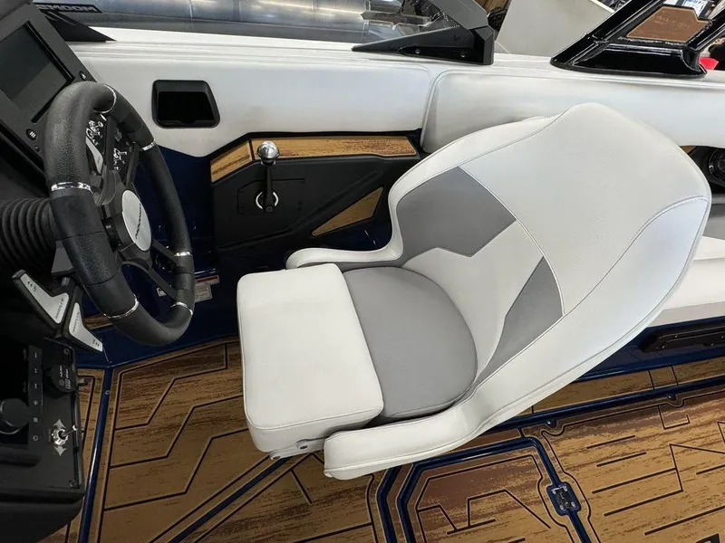 Slide: The Image of 2025 Moomba Mojo boat interior with white and gray seating, modern steering wheel, and wood-patterned flooring. - 9