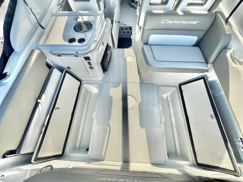 Slide: The Image of 2025 Crownline 280 DC boat interior with seating, kitchenette, and storage compartments. - 34