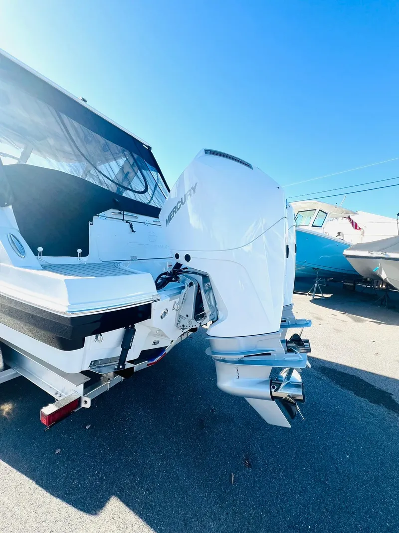 Slide: The Image of 2025 Crownline 280 DC boat with Mercury outboard engine, docked under clear blue sky. - 47