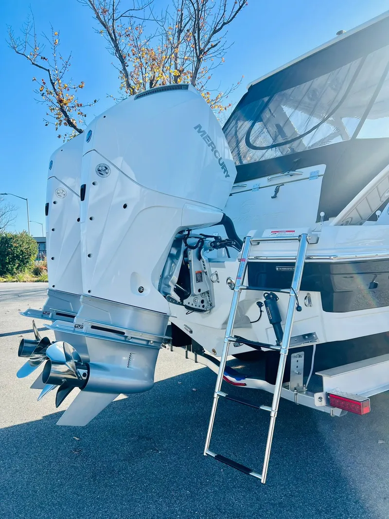 Slide: The Image of 2025 Crownline 280 DC boat with Mercury outboard motor and ladder, parked outdoors. - 48