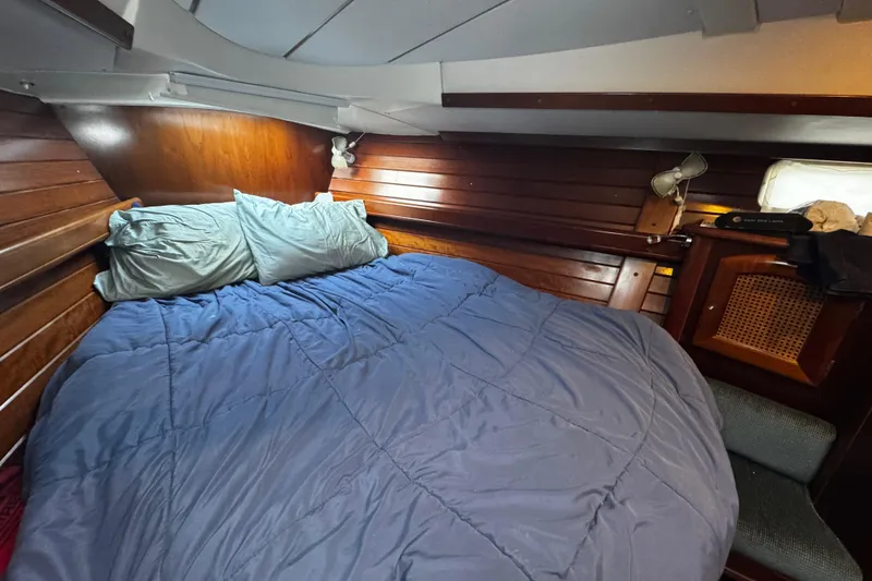 Slide: The Image of Cozy cabin interior of 1999 Beneteau Oceanis Clipper 461 with wooden paneling and bedding. - 100