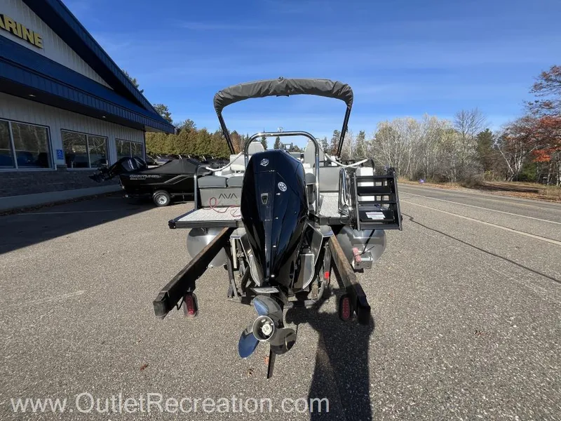 Slide: The Image of 2024 Avalon LSZ Versatile Rear Bench boat with outboard motor in parking lot. - 7