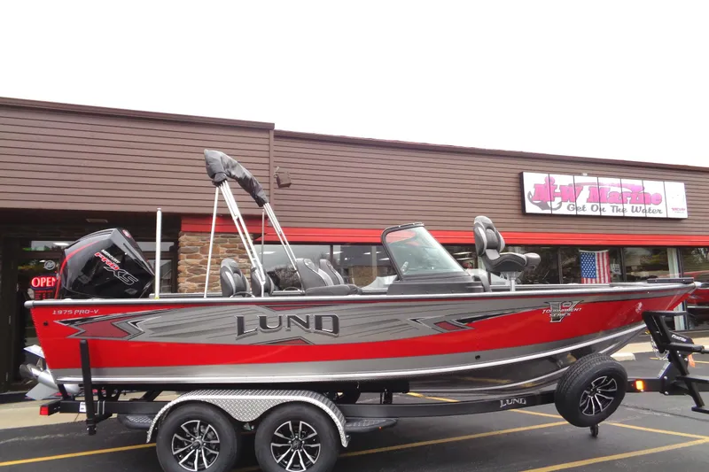 The Image of Red and silver 2025 Lund 1975 Pro-V boat on trailer outside a store. - 0
