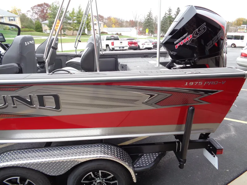 Slide: The Image of 2025 Lund 1975 Pro-V boat with red and silver detailing, parked on a trailer. - 10