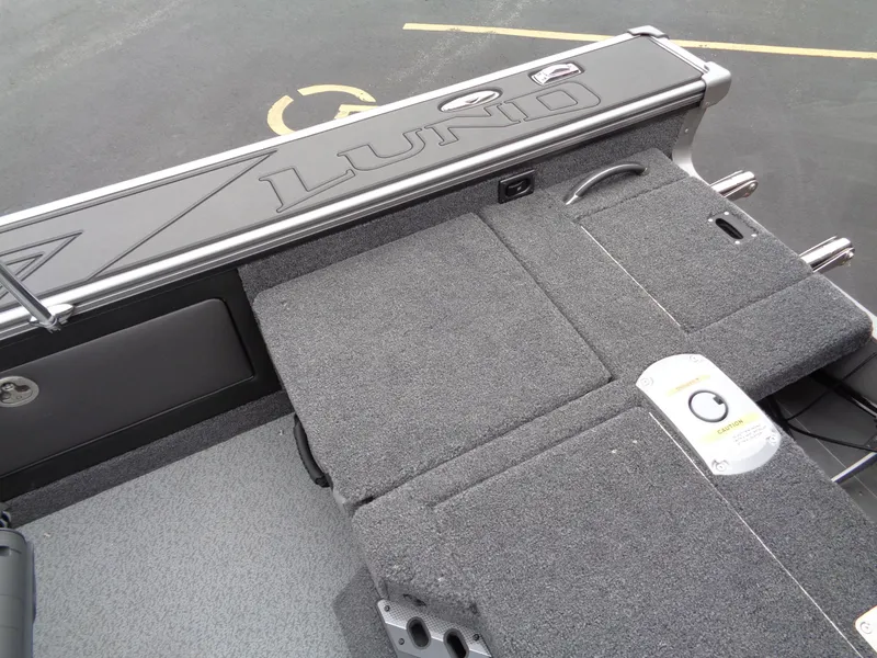 Slide: The Image of 2025 Lund 1975 Pro-V boat interior with gray carpet and storage compartments. - 18