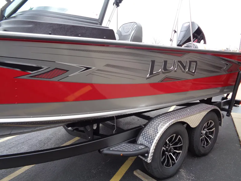 Slide: The Image of 2025 Lund 1975 Pro-V boat with red and gray design on a trailer. - 7