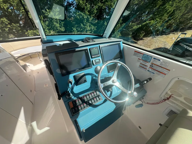 Slide: The Image of 2017 Pursuit 325 DC Dual Console boat cockpit with steering wheel and control panel. - 12