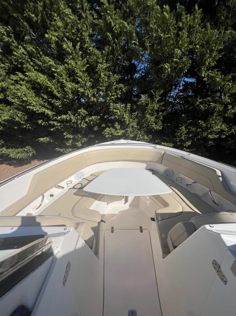 Slide: The Image of 2017 Pursuit 325 DC Dual Console boat with spacious seating and lush greenery backdrop. - 17
