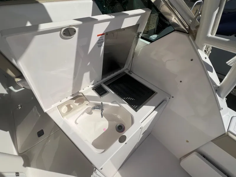 Slide: The Image of 2017 Pursuit 325 DC Dual Console boat interior with sink and storage area. - 19