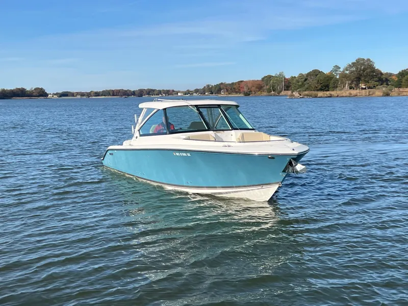 Slide: The Image of 2017 Pursuit 325 DC Dual Console boat on calm water, clear sky background. - 2