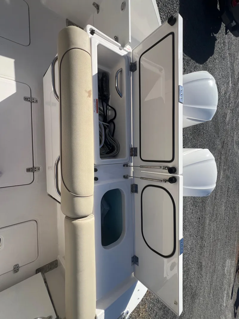 Slide: The Image of 2017 Pursuit 325 DC Dual Console boat storage compartment with open doors. - 20