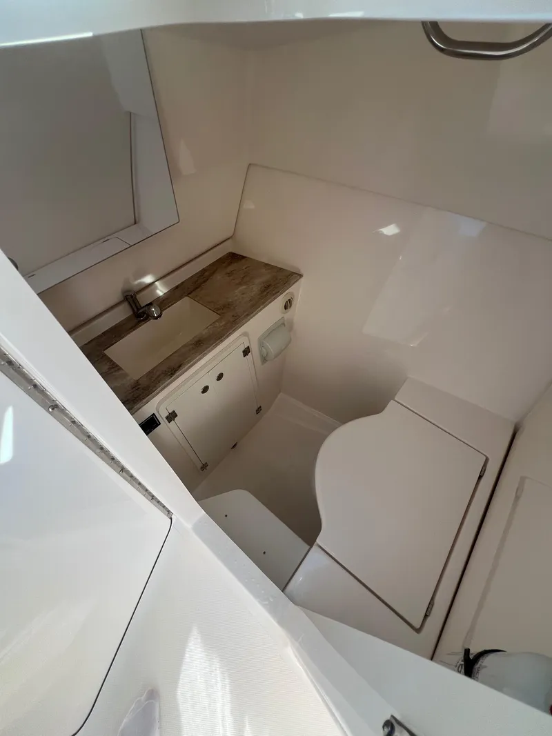 Slide: The Image of Interior of 2017 Pursuit 325 DC Dual Console boat, featuring compact bathroom amenities. - 22