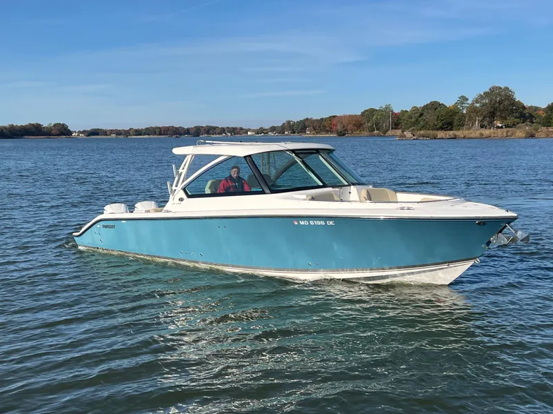 Slide: The Image of 2017 Pursuit 325 DC Dual Console boat on calm water, blue hull, scenic background. - 25