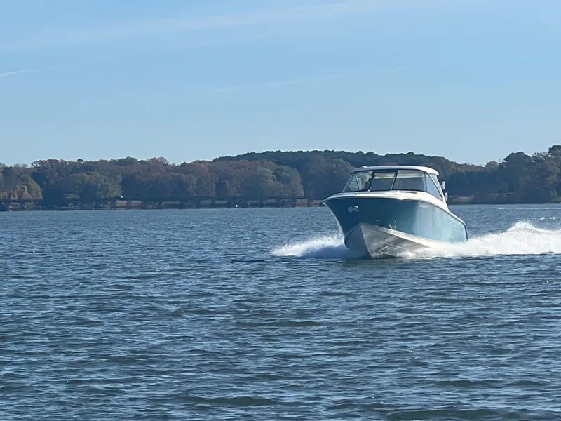 Slide: The Image of 2017 Pursuit 325 DC Dual Console boat cruising on a lake. - 33