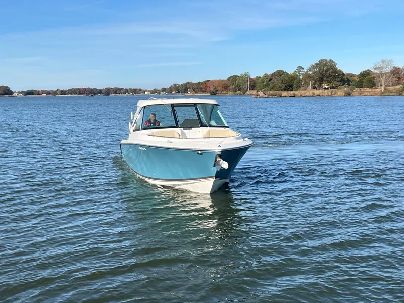 Slide: The Image of 2017 Pursuit 325 DC Dual Console boat cruising on a serene lake. - 6