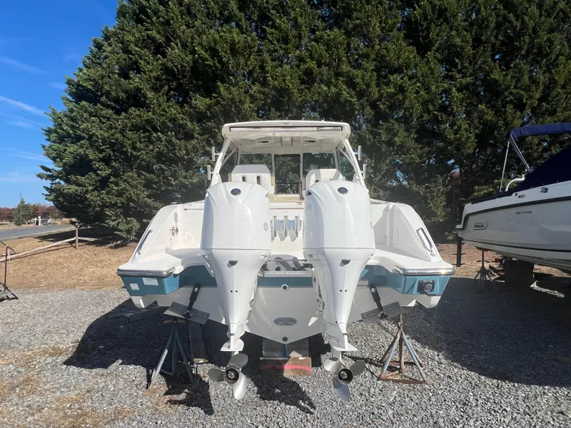 Slide: The Image of 2017 Pursuit 325 DC Dual Console boat with twin engines, parked on gravel. - 8