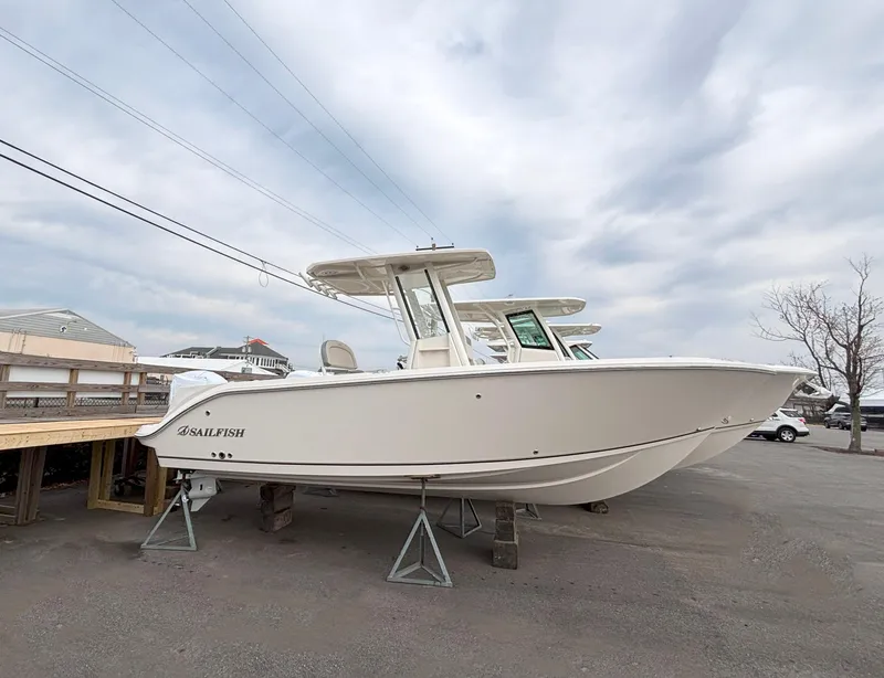 The Image of 2025 Sailfish 232 CC boat on display, elevated on stands, under a cloudy sky. - 0