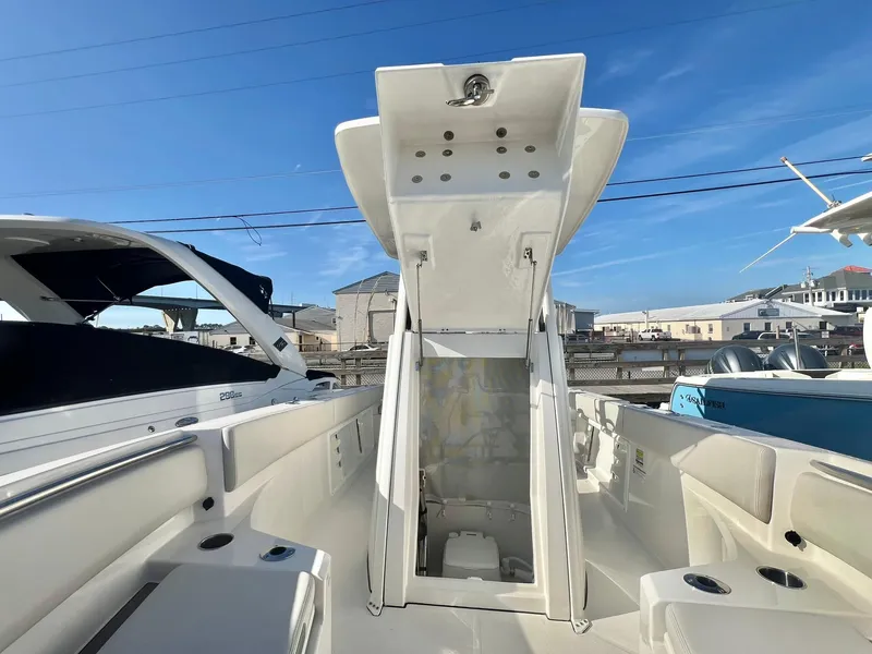 Slide: The Image of 2025 Sailfish 232 CC boat interior with open storage compartment, docked under clear blue sky. - 20