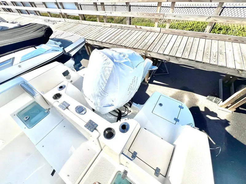Slide: The Image of 2025 Sailfish 232 CC boat with covered outboard motor, docked near wooden pier. - 21