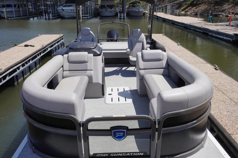 Slide: The Image of 2024 Premier 250 Sunsation pontoon boat with spacious seating, docked at a marina. - 2