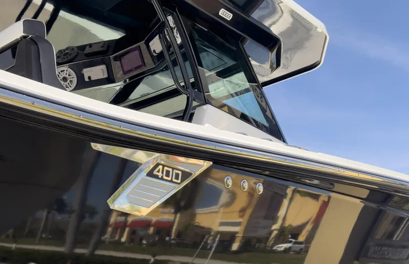 Slide: The Image of 2024 Blackfin 400 CC boat, sleek design, modern dashboard, and reflective exterior under blue sky. - 20