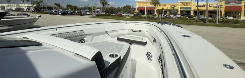 Slide: The Image of 2024 Blackfin 400 CC boat interior with seating and speakers, parked near shops. - 27