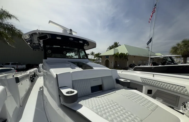 Slide: The Image of 2024 Blackfin 400 CC boat with sleek design, docked near a building and flag. - 31