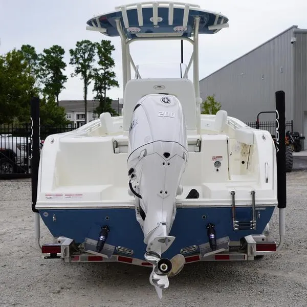 Slide: The Image of 2025 Cobia 220 Center Console boat with powerful outboard motor, parked on gravel. - 3