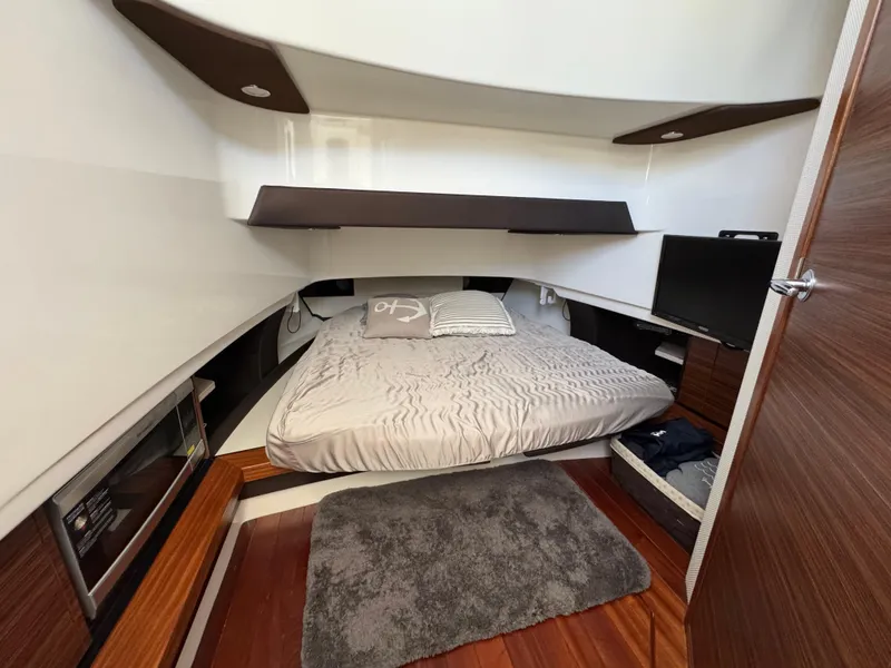 Slide: The Image of 2019 Pursuit S 368 Sport cabin with bed, TV, and wooden accents. - 16