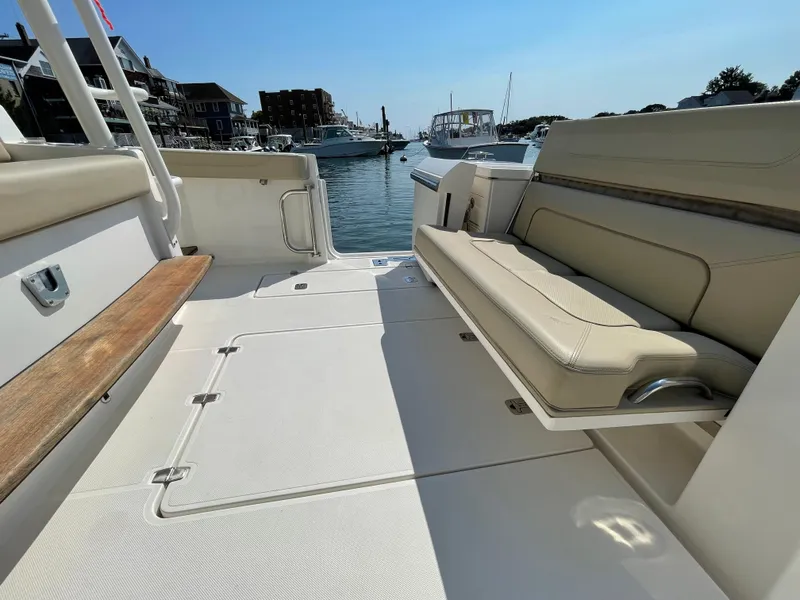 Slide: The Image of 2019 Pursuit S 368 Sport boat interior with beige seating, docked in a marina. - 28